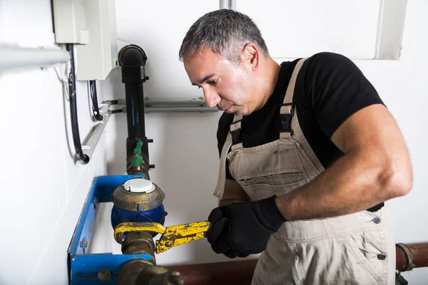 Plumber repairing metallic water pipes with wrench