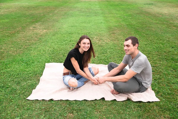 Ungt par sitta på en filt på gräset — Stockfoto