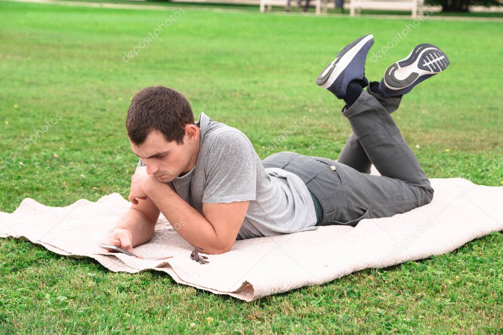 Man lying on blanket on grass with mobile