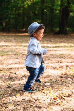 Gülümseyen ve açık havada çalışan şapkalı şirin küçük çocuk