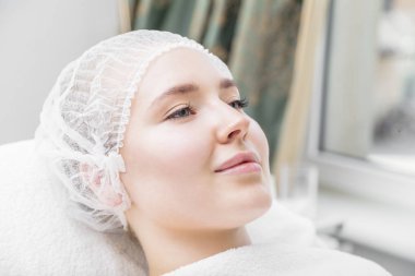 Gülümseyen genç kadın kozmetik kanepede yatıyor.