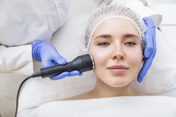 Kosmetyk wykonuje zabieg masażu ultradźwiękowego na kobiecej twarzy — Zdjęcie stockowe