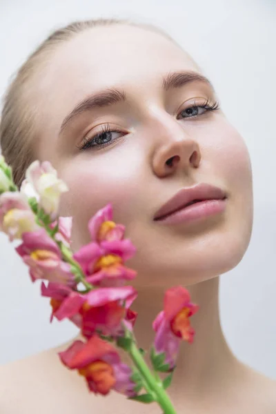 Beautiful girls face with color flower near — Stock Photo, Image