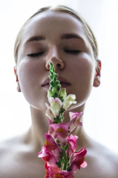 Hermosa joven oliendo flor de snapdragon brillante —  Fotos de Stock