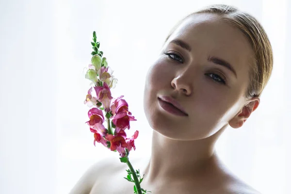 Beautiful girl smelling bright colored nsapdragon flower — Stock Photo, Image