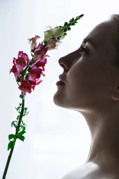 花をスニッフィングのプロファイルで若い女の子の顔 — ストック写真