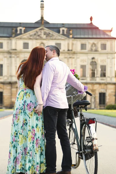 Поцелуи и прогулки пара с велосипедом возле дворца — стоковое фото