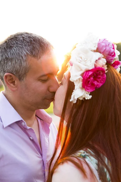 Man kysser kvinna bär blomma krans i parken — Stockfoto