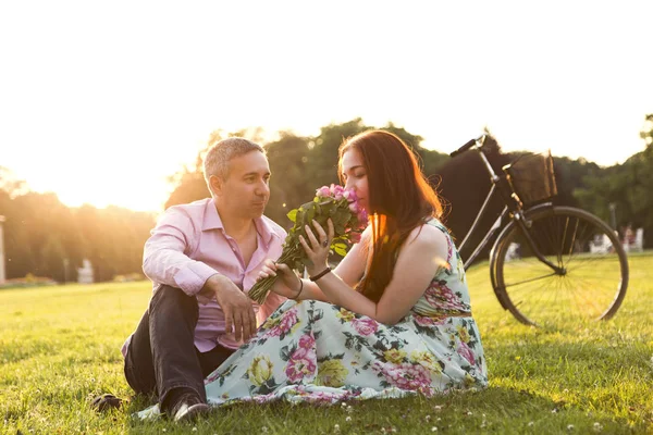 Mann und Frau mit Blumen sitzen neben Fahrrad — Stockfoto