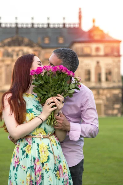 Par på date kysser gömmer sig bakom rosor bukett — Stockfoto