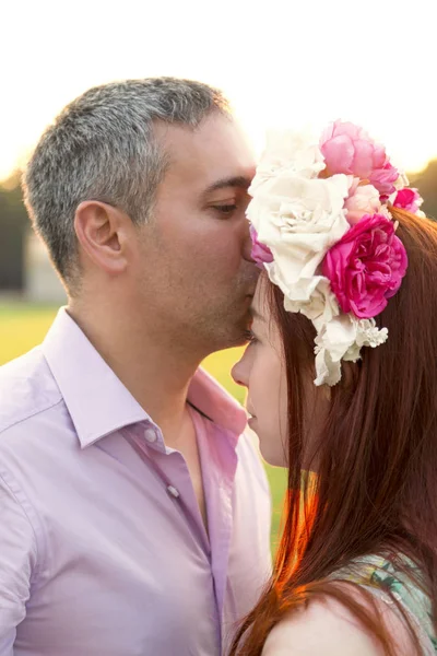 Mann küsst Frau in Blumenkranz auf den Kopf — Stockfoto