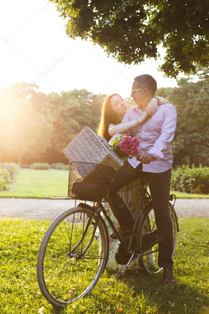 Happy couple going on picnic by bike in sunny day