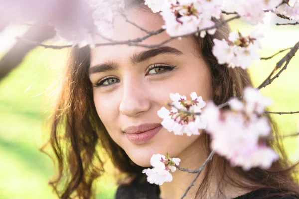 Chicas cara en el marco de la rama de árbol de flor al aire libre — Foto de Stock