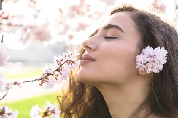 Дівчина із задоволенням пахне гілкою з квітами — стокове фото