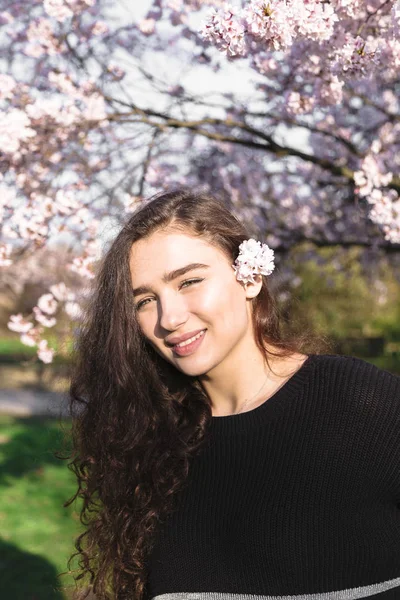 Chica de pie en el fondo de cerezo flores árbol — Foto de Stock