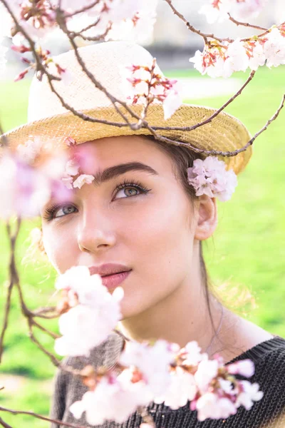 Hasır şapkalı kız rüya gibi çiçek dalına bakar