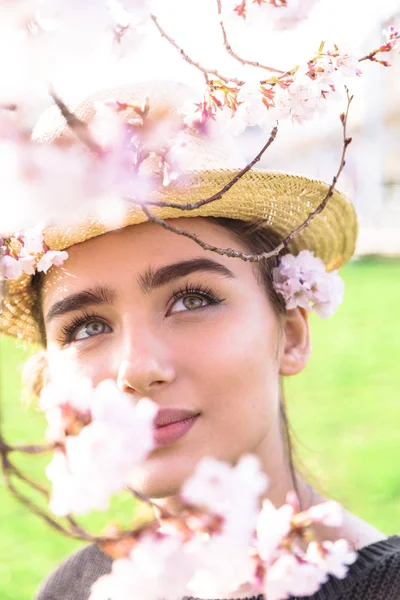 Hasır şapkalı kız çiçekli dalı arkasına saklandı