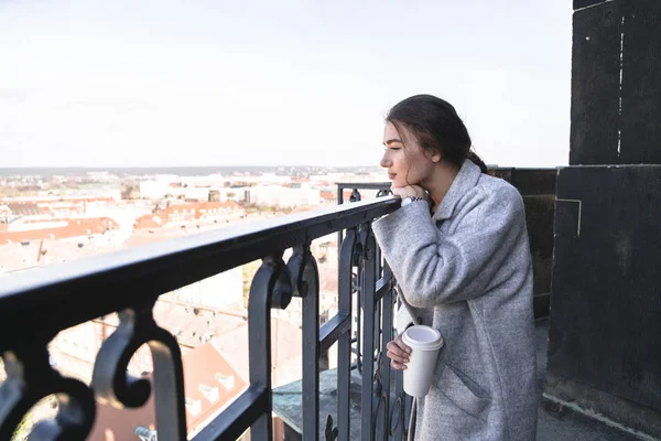 Menina fica na varanda com xícara de café na mão — Fotografia de Stock