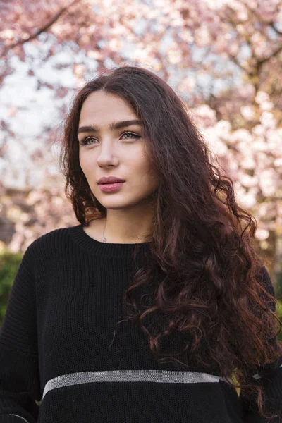 Girl with flowing hair against blooming tree