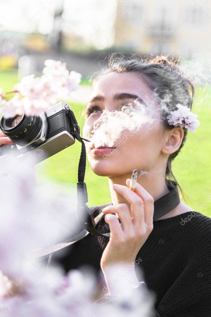 Girl takes photo and smokes, looking away