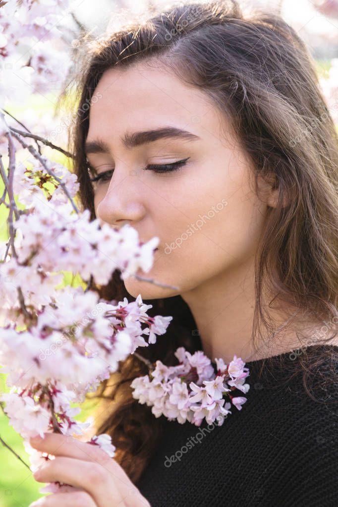 Portrait of beautiful girl sniffs flowering branch