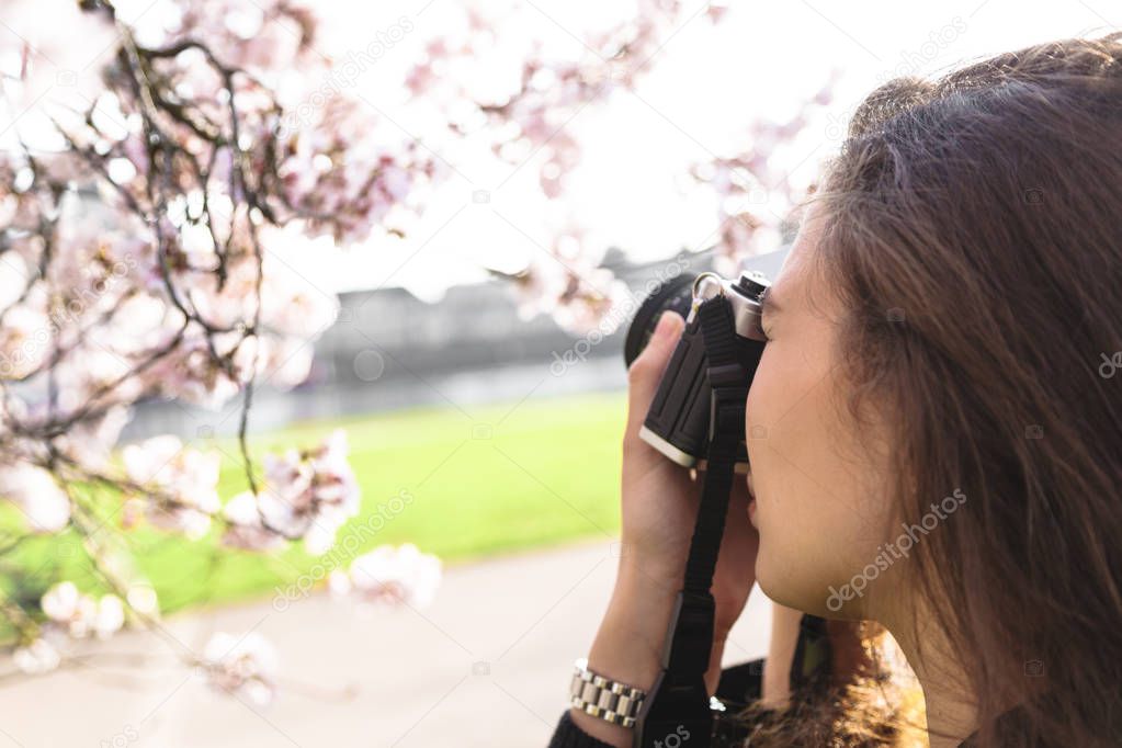 Portrait of girl making photo of flowering tree
