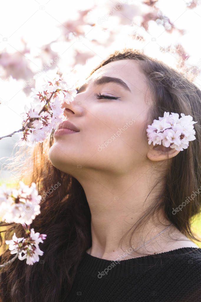 Girl with pleasure smells branch with flowers
