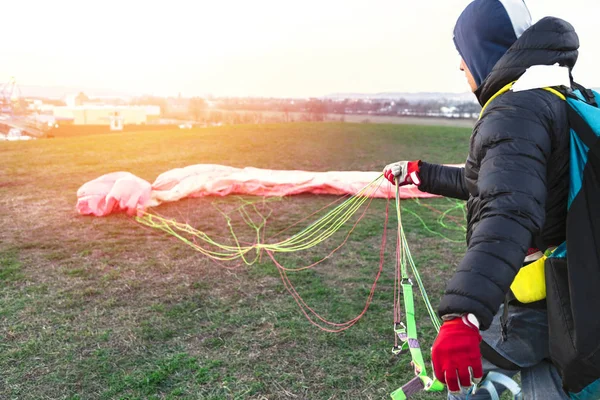 Man folds parachute after landing on green field — Stock Photo, Image