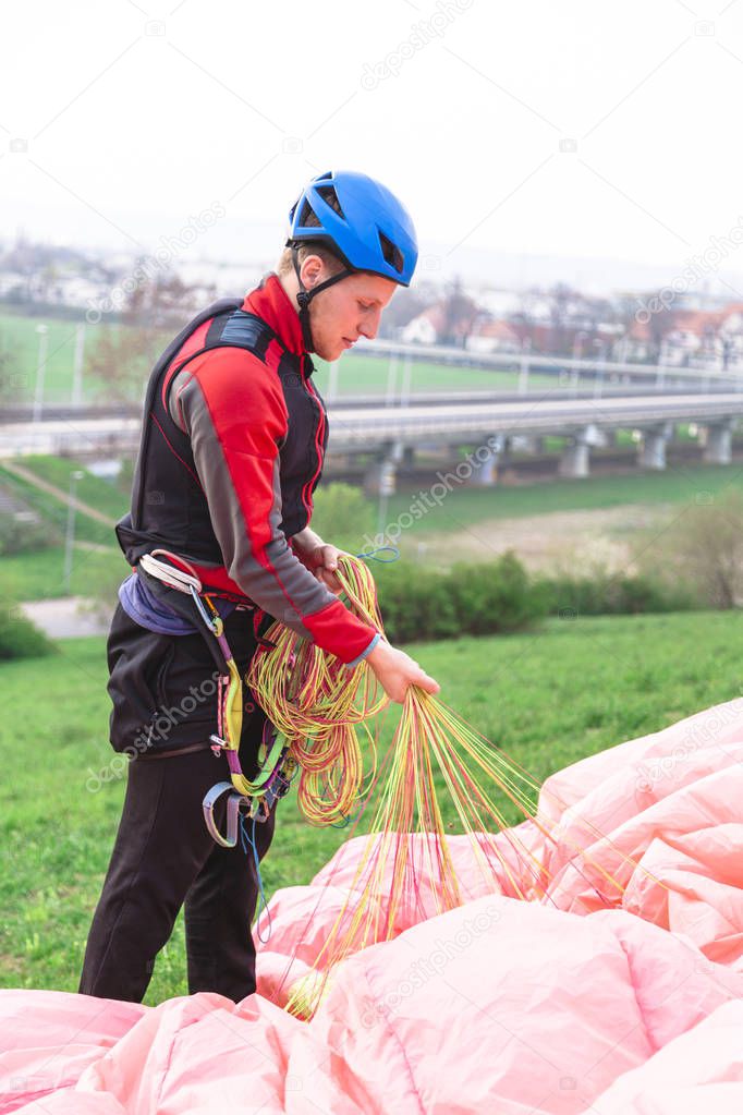Paraglider landed after jump and raises parachute