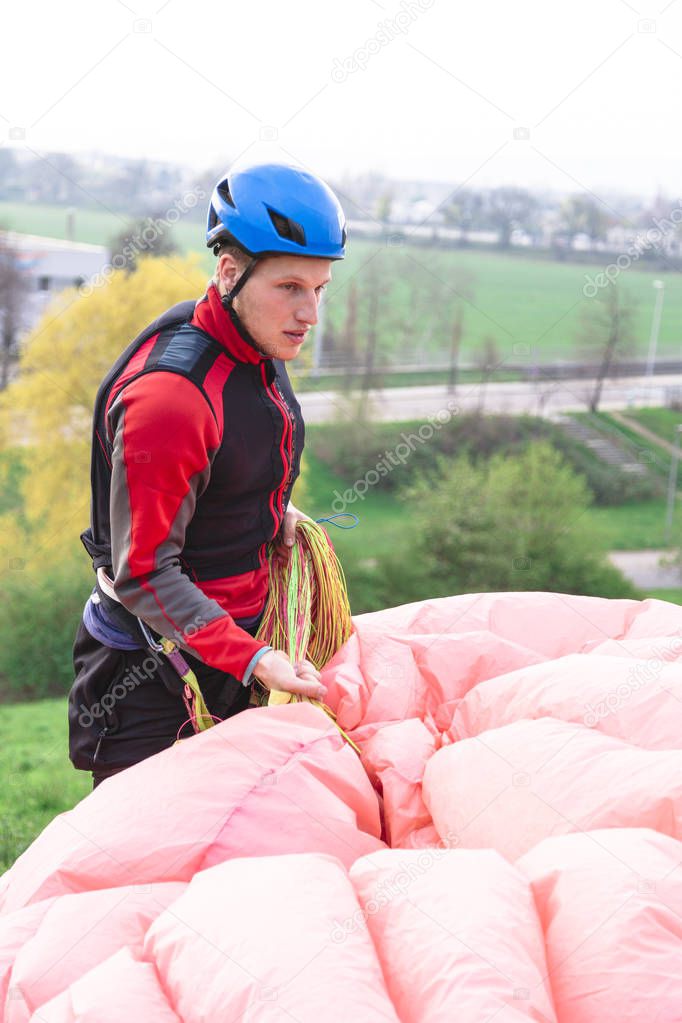 Paraglider landed after jump and raises parachute