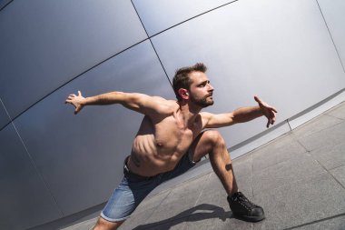 Yoga da ayakta dans eden genç adam sokakta poz veriyor