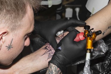 Siyah eldivenli adam daire şeklinde dövme doldurur