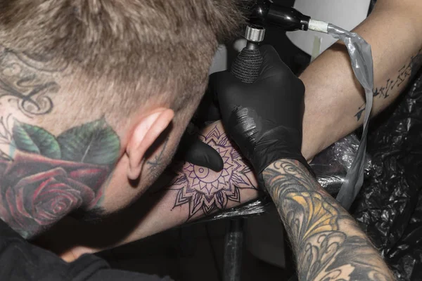 Tetovaný mistr dělá tetování ve formě mandaly — Stock fotografie