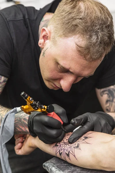 Young man makes tattoo concentrating on process