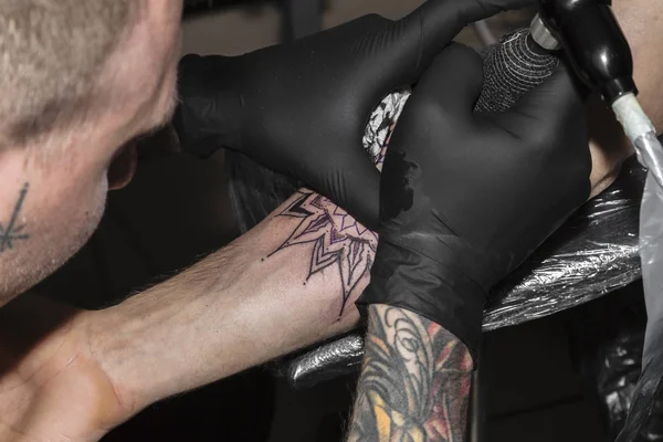 Руки художника татуювання в рукавичках на роботі крупним планом — стокове фото