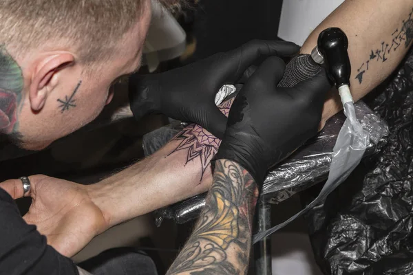 Dövme sanatçısı dövme salonda yandan dövme yapıyor