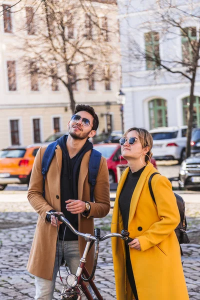 Junges internationales Paar steht mit Fahrrad in Mänteln — Stockfoto