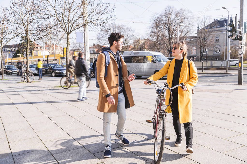 Young latin man walks near woman with bicycle