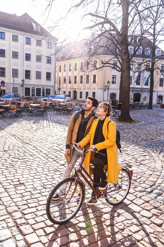 Young mixed race couple walking in city with bike