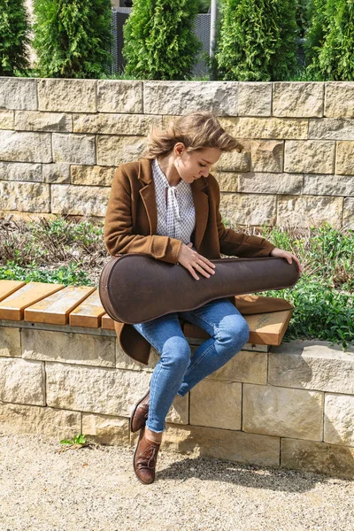 Mujer joven con violín sentada en un banco de madera —  Fotos de Stock
