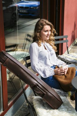 Kafe terasında kahve içen genç kemancı