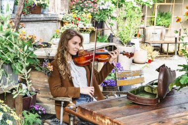 Genç kız ahşap sandalyeye oturur ve keman çalar