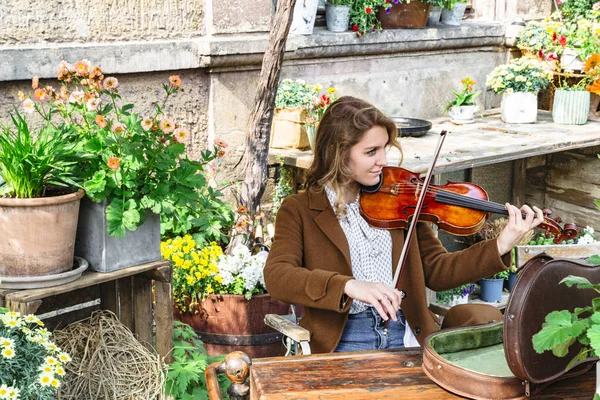 Jovem mulher senta-se no jardim de outono tocando violino — Fotografia de Stock