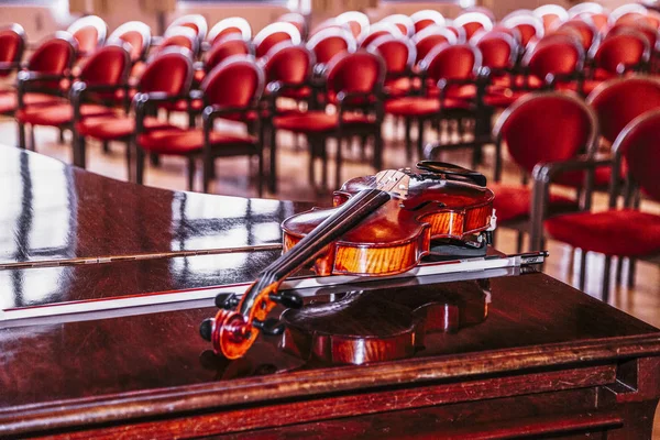 Violin lies on piano on backround of blurred hall