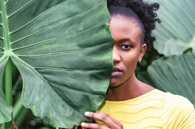 Afrikalı kız büyük yeşil yaprak arkasında yüzünü sakladı