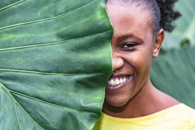 Palmiye yaprağının arkasına saklanan Afrikalı kızın yakın yüzü