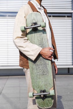 Afrikalı adam el Closeup yeşil kaykay tutar