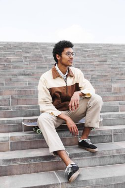 Afrikalı kaykaycı oturma ve merdivenlerde istirahat