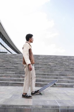 Afro kaykaycı sokakta kaykay üzerine bastı