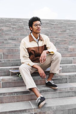 Afrikalı kaykaycı oturma ve merdivenlerde istirahat